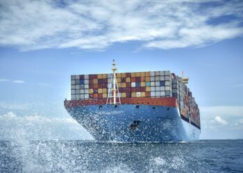 Volvo change to renewable fuel for ocean freight, cutting CO2 emissions by 84%, MTB Events, Image shows a large ship carrying colourful freight boxes on the ocean with ocean spray in the fore front and light cloud in the background