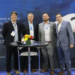 AerFin Ltd appoints B&H Worldwide to manage inventory in Singapore and Australia., MTB Events, Image shows members of Aerfin & B&H standing alongside eachother behind a black table with flowers on top. In the background there is a large image of a plane.