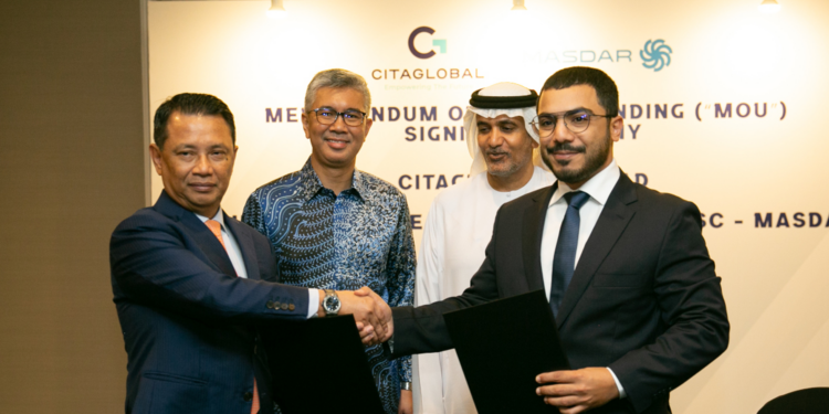 Masdar & Citiglobal Berhand sign MoU to develop renewable energy across Malaysia, MTB Events. Image shows Abdulla Zayed and Tan Sri (Dr) Mohamad Norza Zakaria shaking hands in front of Yang Berhormat Mulia Datuk Seri Utama Tengku Zafrul Aziz HE Khalid Ghanim Mohammed Alghaith. In the background there is a large poster with Citigroup and Masdar logos.