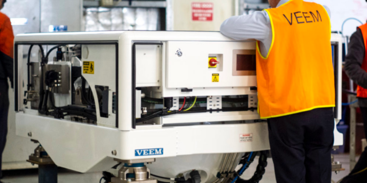 Strategic Marine & VEEM sign gyrostabilizer exclusivity agreement, MTB Events. Image shows a man in a florescent orange jacket with 'VEEM' on the back, looking over a gyrostabilizer