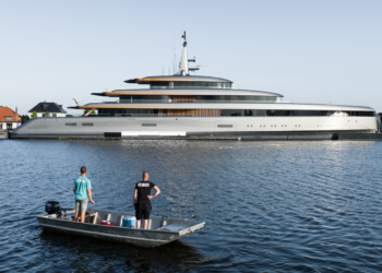 Feadship's Obsidian sets a higher standard for carbon reduction, MTB Events, image shows the superyacht, 'Obsidian', in the ocean with two men standing on a small boat looking at the yacht