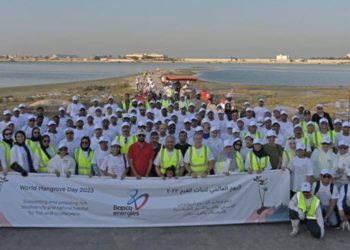 Bapco Energies continues their modernisation project with mangrove plantation & beach clean up, MTB Events. Image shows participants of the clean up on the Ma'ameer shore holding a large sign with the title 'World Mangrove Day 2023'.