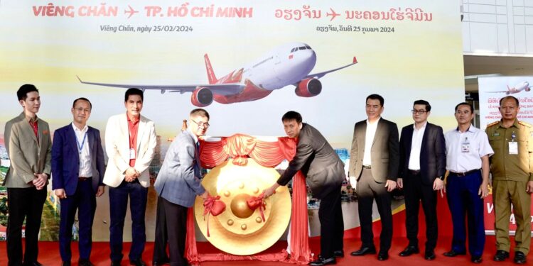 Vietjet celebrate new connections between Ho Chi Minh City with Vientiane, MTB Events. Image shows the ceremony with members of both airlines and cultural representatives of both countries banging a dong in front of a large Vietjet promotional image
