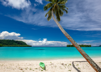 Direct flights to Vanuatu announced by Qantas and Jetstar, MTB Events. Image shows a beach with a green kayak and palm tree, Vanuatu.