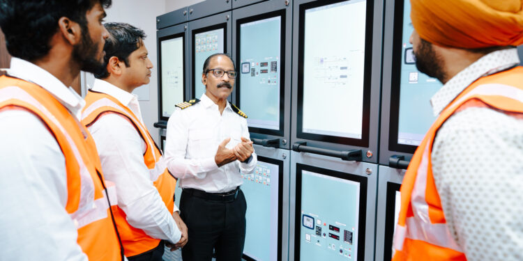 Image shows 4 men in orange jackets - Seafarer training on alternative fuels: the new methanol bunkering simulator from Wärtisä at BSM's Maritime Training Centre in Kochi ©BSM. BSM Unveils First Methanol Bunkering Simulator at Kochi Training Centre in Collaboration with Wärtsilä, MTB Events.