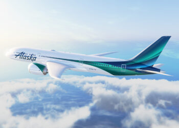 Image shows an Alaska Airlines plane with green and blue stripes on the fuselage flying in the sky with clouds below. Alaska Airlines Expands International Reach with New Routes to London and Reykjavik, MTB Events.