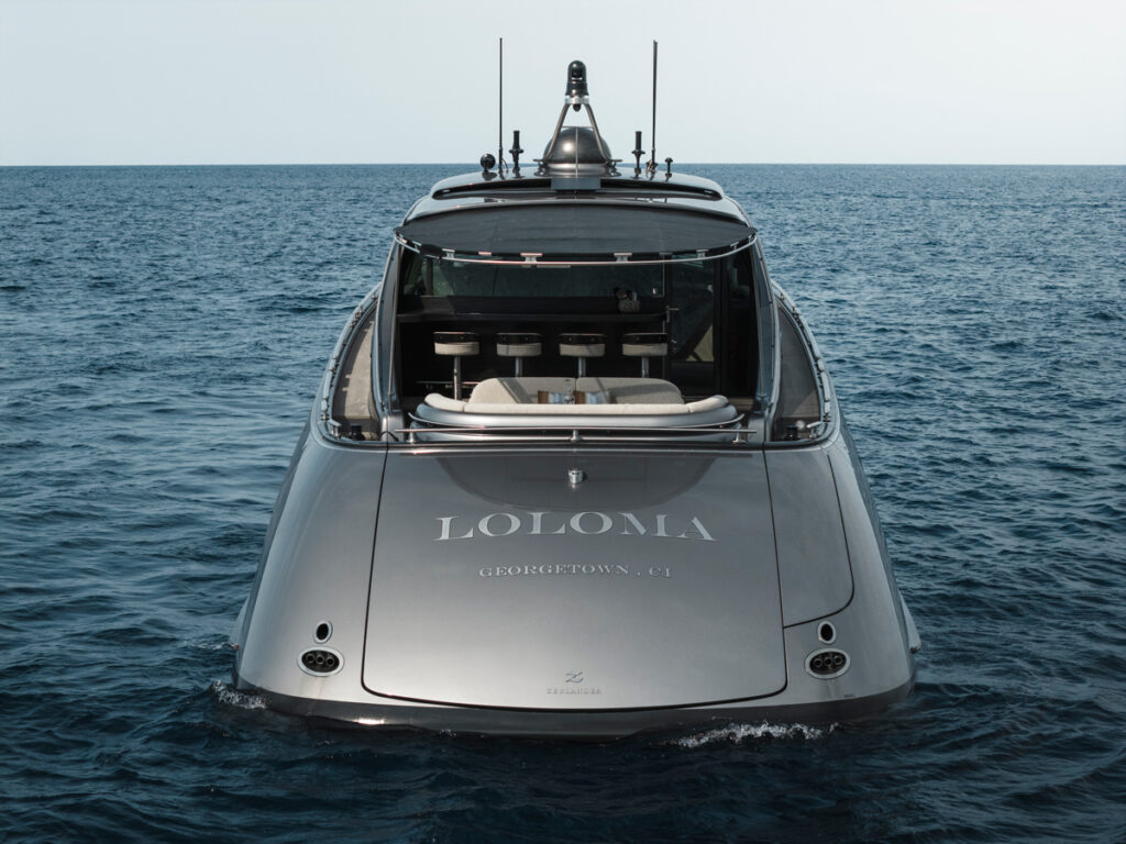 Image shows the back hull of a grey-silver Superyacht with the text 'Loloma, Georgetown' on the lower edge. The yachtis on dark blue water. Zeelander Yachts Delivers Custom Zeelander 7, Loloma, MTB Events.