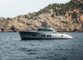 Image shows the superyacht titled Loloma on the sea with a backdrop off a cliffside. Zeelander Yachts Delivers Custom Zeelander 7, Loloma, MTB Events.