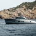Image shows the superyacht titled Loloma on the sea with a backdrop off a cliffside. Zeelander Yachts Delivers Custom Zeelander 7, Loloma, MTB Events.