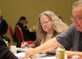 Image shows a man and a woman side on towards the camera pointing at a document on a table, with another woman in the foreground. From Meetings to Memories: Reflecting on MTB Aviation Europe 2025, MTB Events.