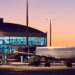 Image shows an airplane being prepared to be boarded at an airport with an orange sky in the background. ACI Unveils Roadmap for Smarter Airport Partnerships, MTB Events.