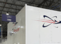 Image shows inside a warehouse building with a large white wall with the text Flight Power, alongside their logo. A Visit to Flight Power’s Plant 98 — Reflections from Holly, MTB Events, MTB Events.