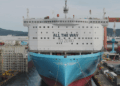 Image shows a large ship in a shipyard surrounded by cranes and machinery, on the front of the ship reads the words "All the way to Zero". HD Hyundai and Palantir Scale AI Platforms Across Global Operations, MTB Events.