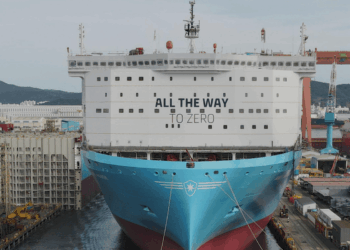 Image shows a large ship in a shipyard surrounded by cranes and machinery, on the front of the ship reads the words "All the way to Zero". HD Hyundai and Palantir Scale AI Platforms Across Global Operations, MTB Events.
