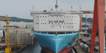 Image shows a large ship in a shipyard surrounded by cranes and machinery, on the front of the ship reads the words "All the way to Zero". HD Hyundai and Palantir Scale AI Platforms Across Global Operations, MTB Events.