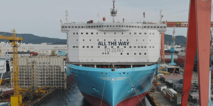 Image shows a large ship in a shipyard surrounded by cranes and machinery, on the front of the ship reads the words "All the way to Zero". HD Hyundai and Palantir Scale AI Platforms Across Global Operations, MTB Events.