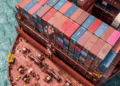 Image shows a top down view of the front side of a red container ship with colourful containers stacked up. Signal Ocean Expands Maritime Intelligence Offering Through AXSMarine Acquisition, MTB Events.