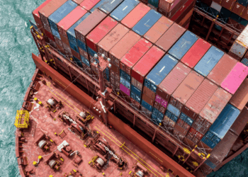 Image shows a top down view of the front side of a red container ship with colourful containers stacked up. Signal Ocean Expands Maritime Intelligence Offering Through AXSMarine Acquisition, MTB Events.
