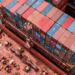 Image shows a top down view of the front side of a red container ship with colourful containers stacked up. Signal Ocean Expands Maritime Intelligence Offering Through AXSMarine Acquisition, MTB Events.