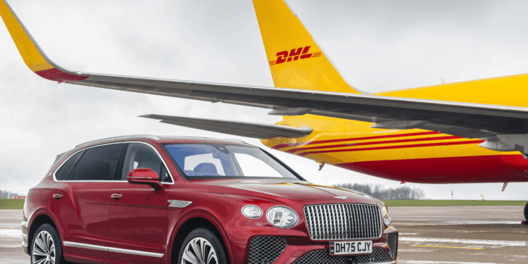 Image shows a red Bentley motor car in the foreground and a yellow and red DHL airfreight airplane in the background, both on a runway. Bentley Motors Transitions to SAF Across Worldwide Air Shipments, MTB Events.