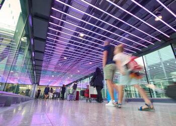 Summer Activities - July 2024. Passengers at London Heathrow Airport in part of terminal with coloured ceiling lights. Record-Breaking Start to 2026 for Heathrow, MTB Events.