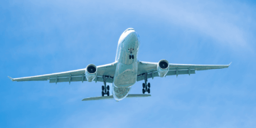 Image shows an aircraft from below as it flies in a blue sky with thin clouds. Engineers Develop Solar-Driven Process for Next-Generation Aviation Fuel, MTB Events.