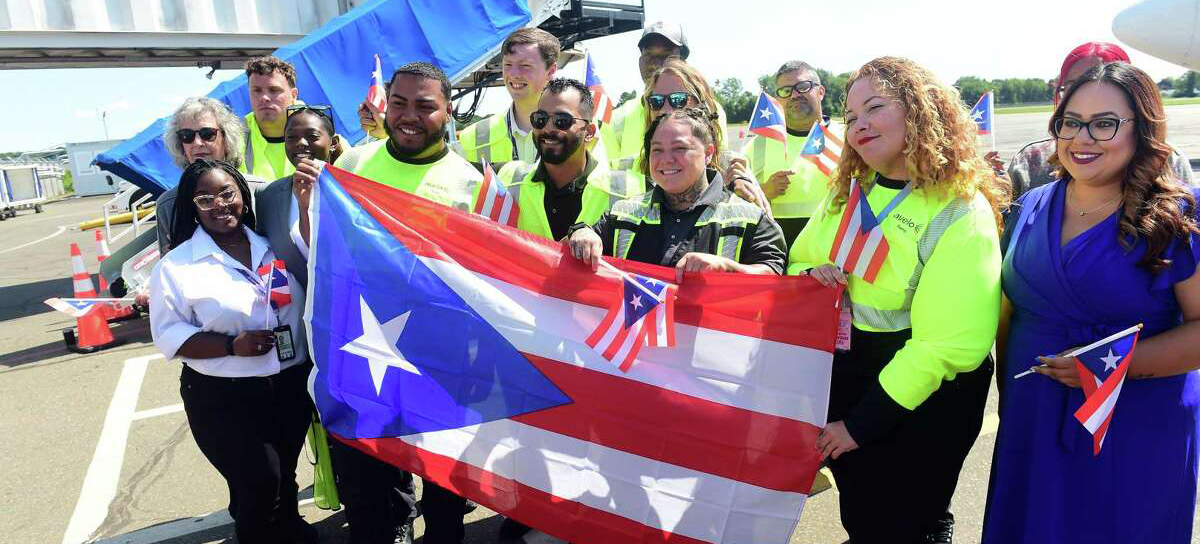 Avelo have begun their descent to San Juan, MTB Events, Image shows airport staff holding a large Puerto Rican flag 
